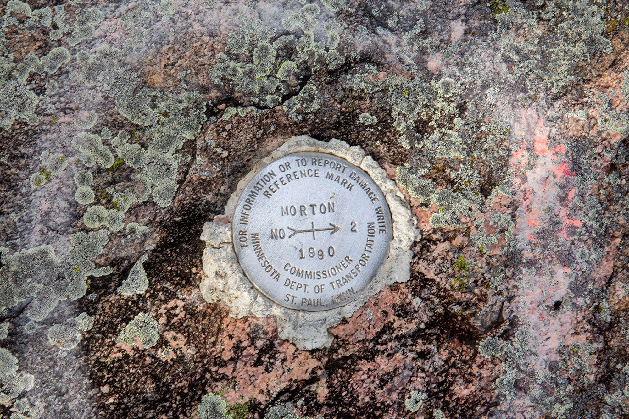 Ramsey Park Redwood Falls 16 Metal reference mark set into rough gray and pink Morton gneiss bedrock in Morton, Minnesota